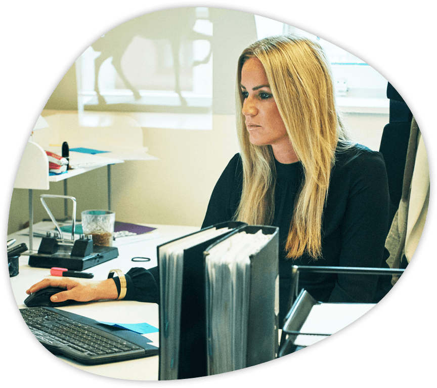 Female accountant with blond hair working on her computer at her desk